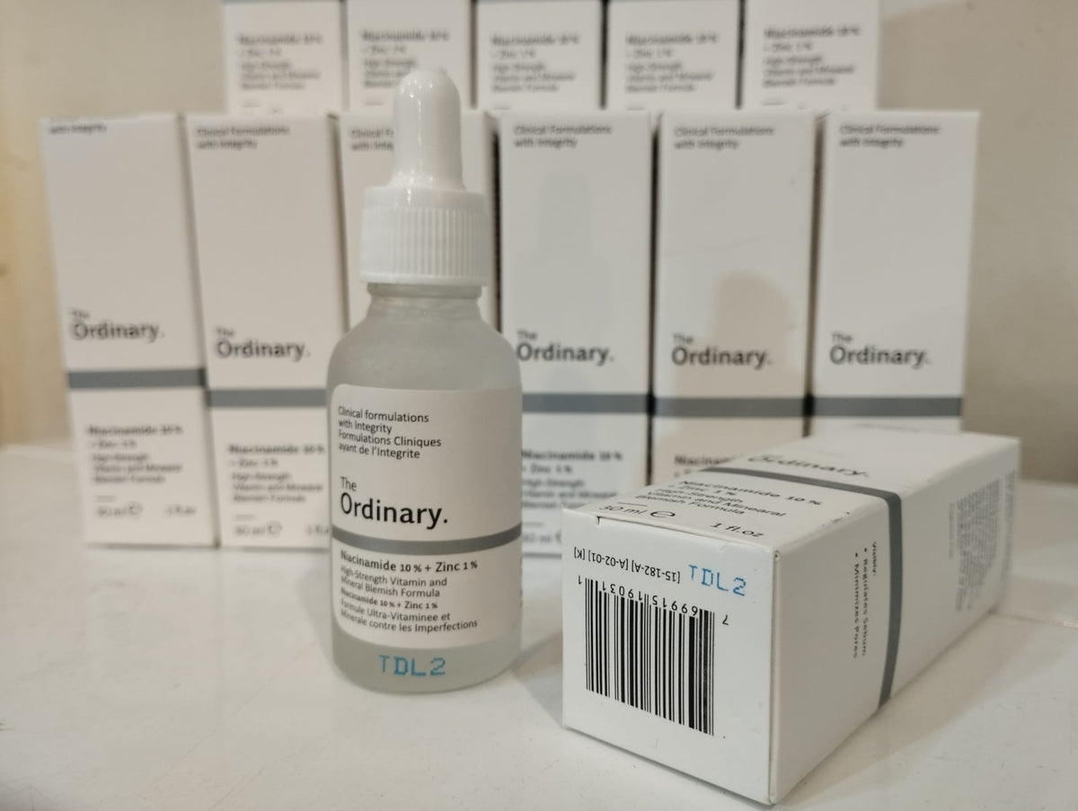 A glass dropper bottle of The Ordinary Niacinamide 10% + Zinc 1% serum standing in front of its packaging box, with multiple matching product boxes neatly arranged in the background.