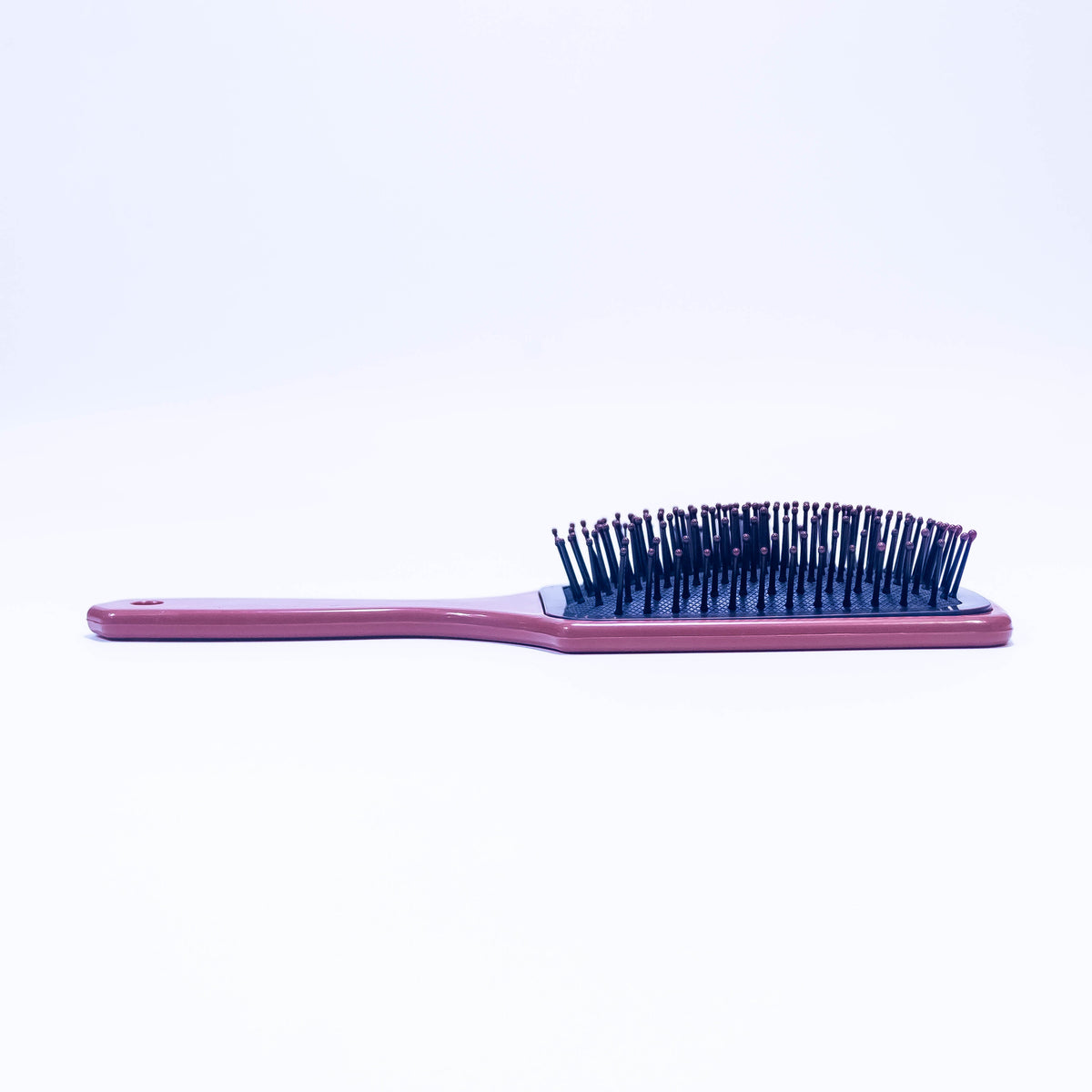 Printed mauve Sauve color hair brush by Zoni Stores, showcasing the textured handle and bristle design.