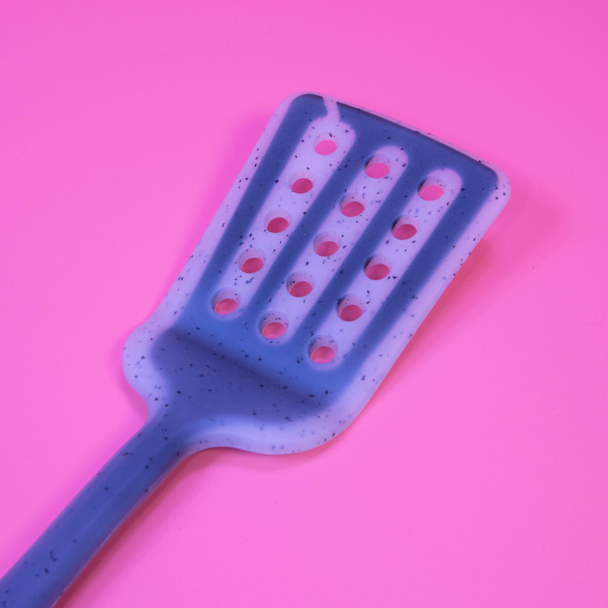 Colorful silicone slotted turner from Zoni Stores with a long handle, ideal for flipping and serving in the kitchen.