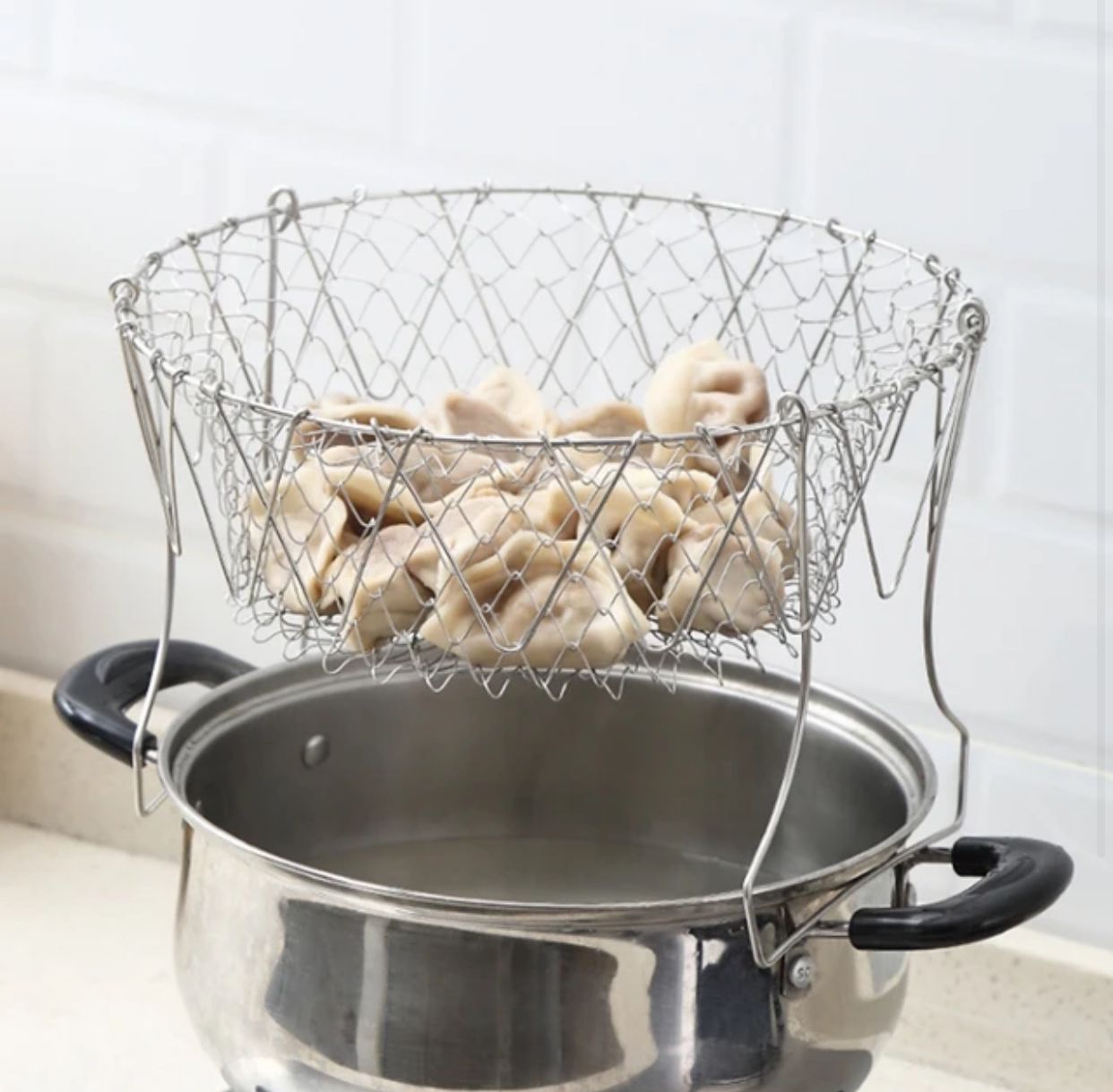 Stainless steel foldable chef basket and strainer hanging on kitchen wall for easy storage at Zoni Stores Pakistan